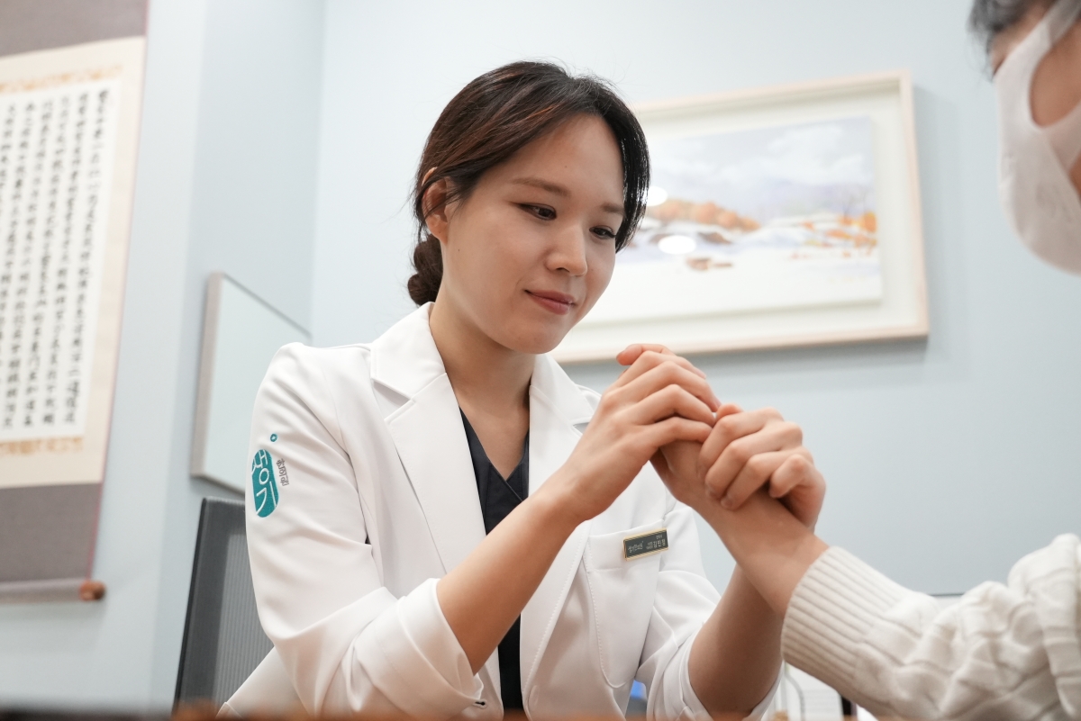 김민정 대표원장이 내원객의 손을 잡고 피부 상태를 직접 살핍니다.