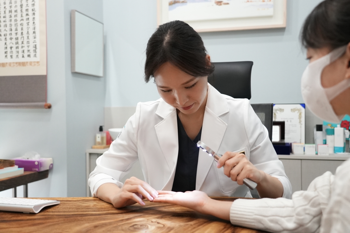 김민정 대표원장이 내원객의 손바닥 피부 상태를 가까이에서 확인합니다.