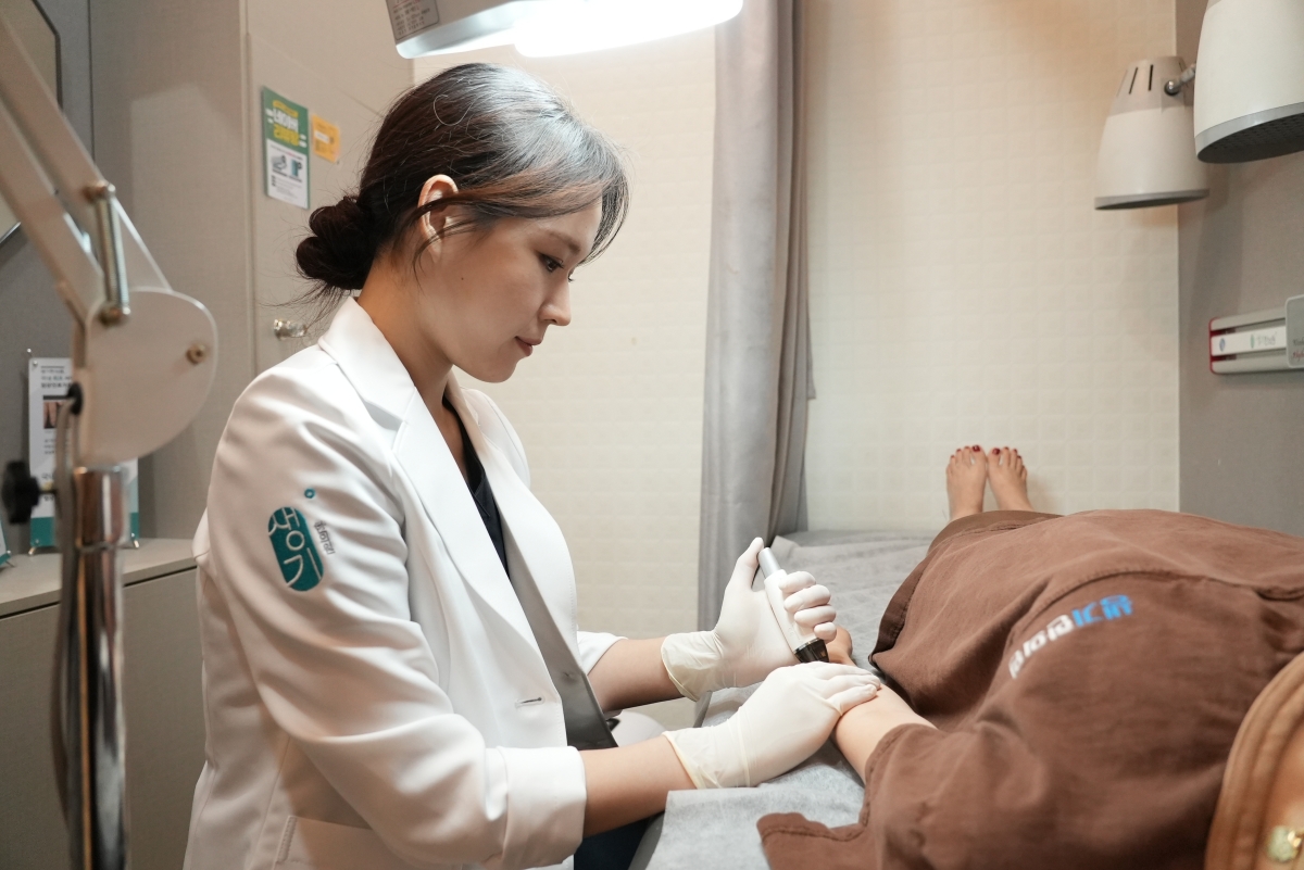 김민정 대표원장이 치료실에서 내원객의 피부 상태를 살피며 치료합니다.